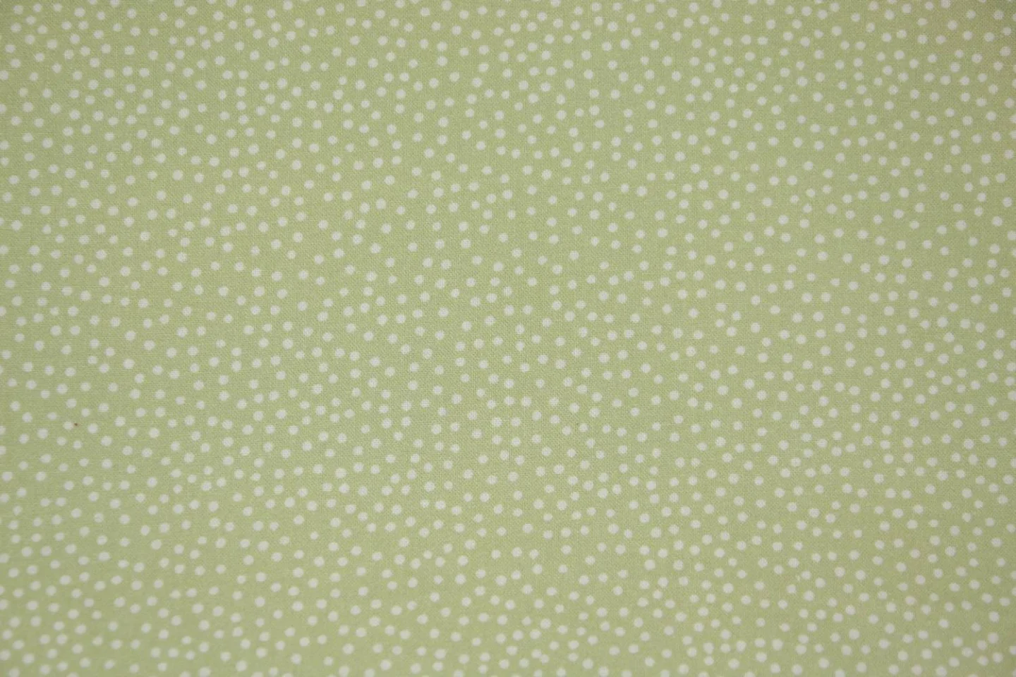 quiltstof-lichtgroen met ivoren stipjes.