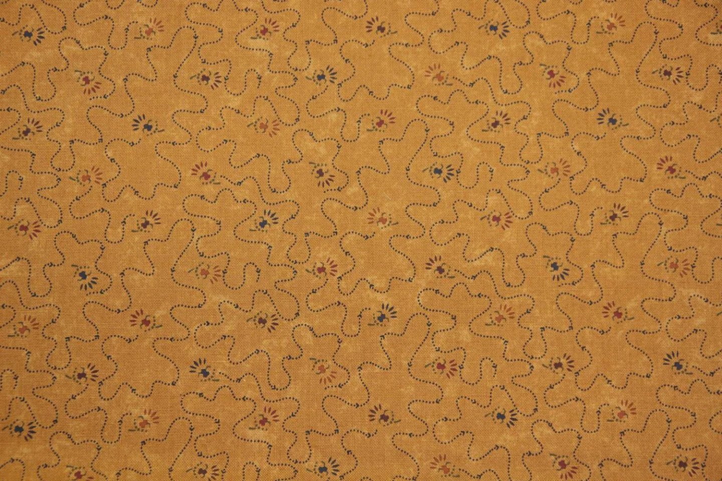 quiltstof-donker okergeel-blauwe stippel.