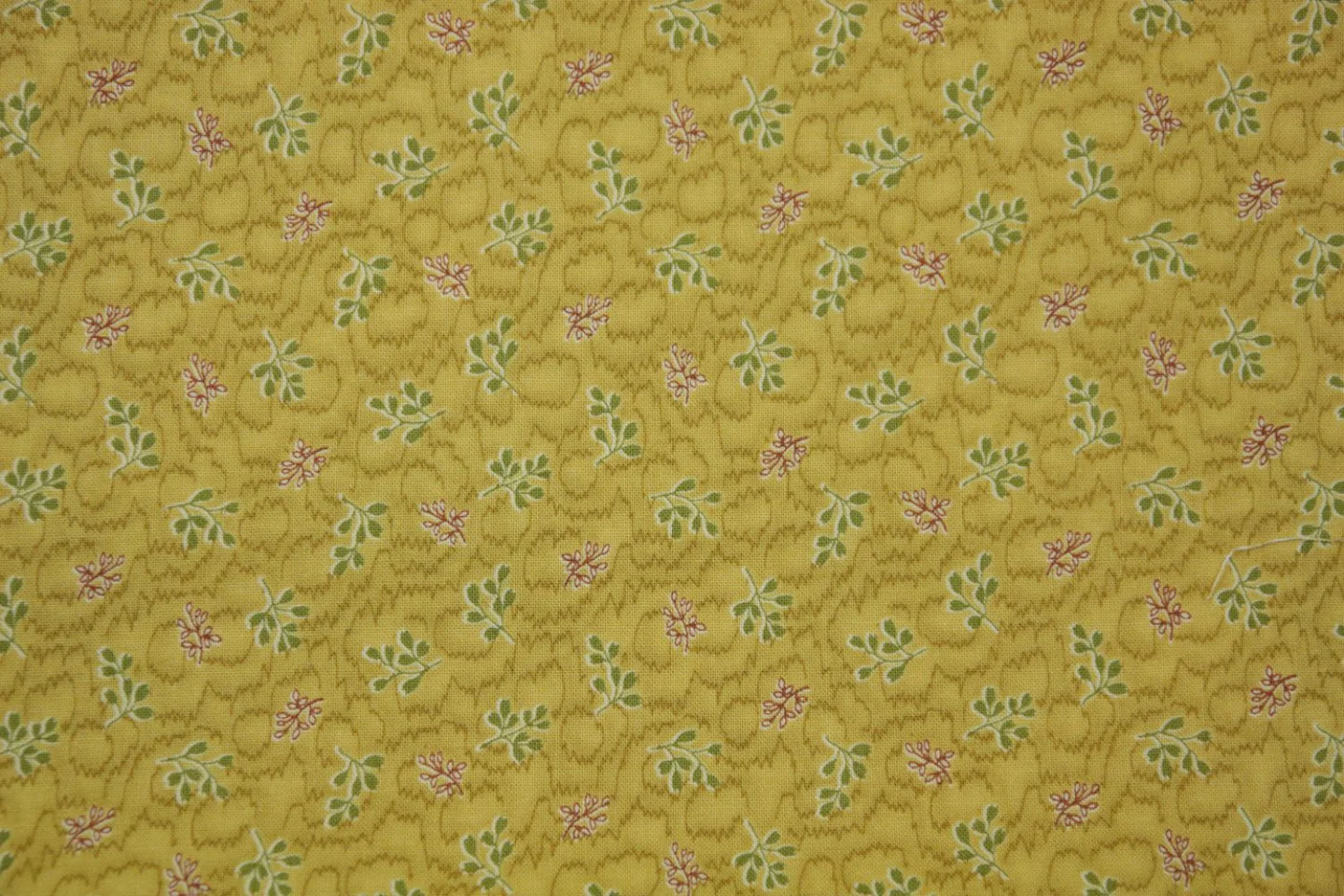 quiltstof-Okergeel, groene en rode takje.