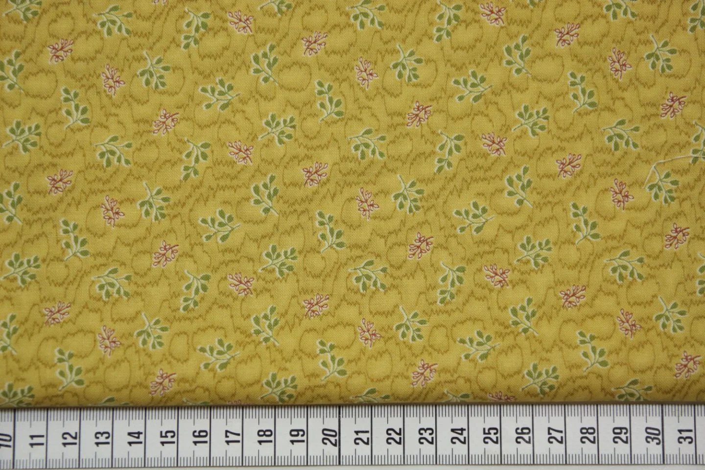quiltstof-Okergeel, groene en rode takje.