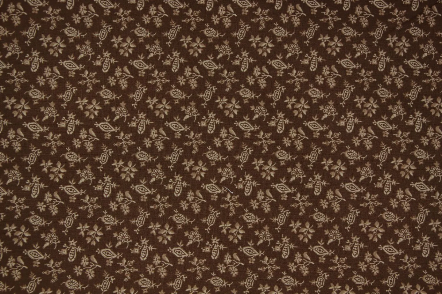 quiltstof-Bruin  met bloemetjes en motie.