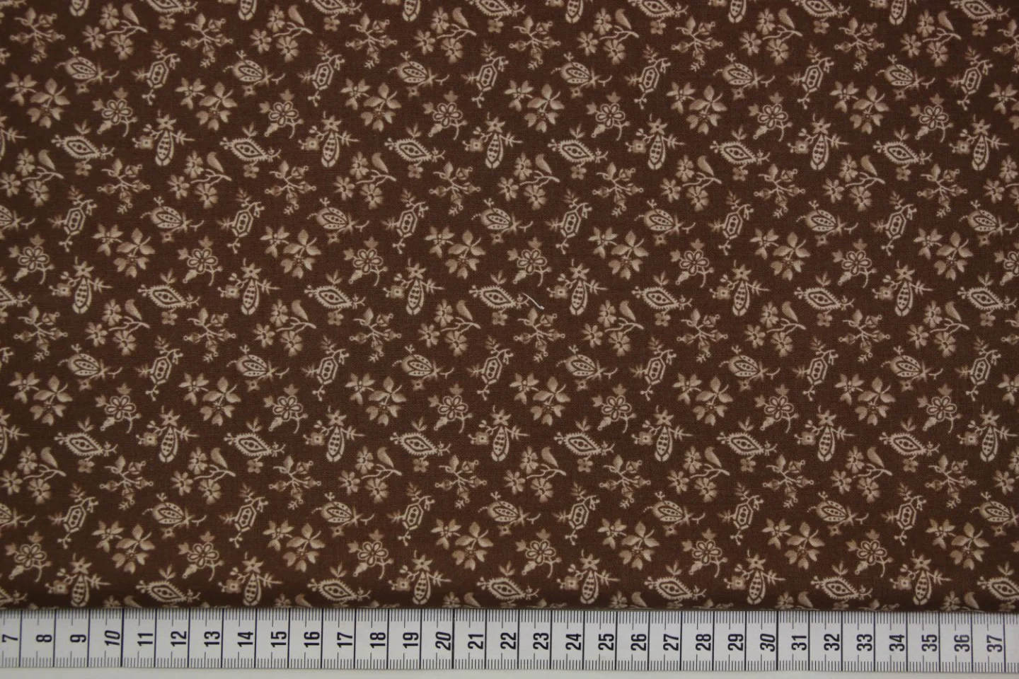quiltstof-Bruin  met bloemetjes en motie.